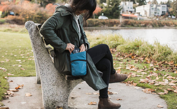 A person accessing their phone from the phone pocket of the P.I.K.A. Pouch.